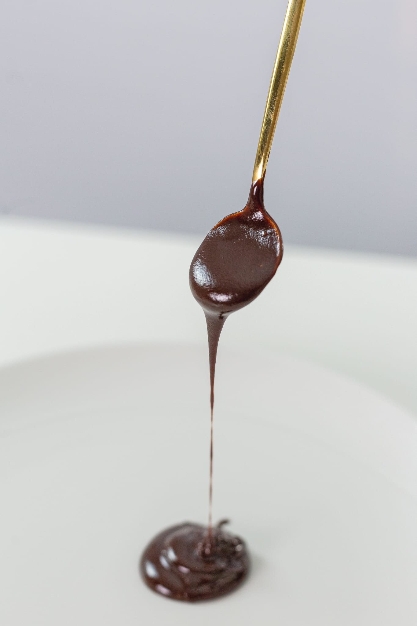 Melted chocolate dripping from a golden spoon