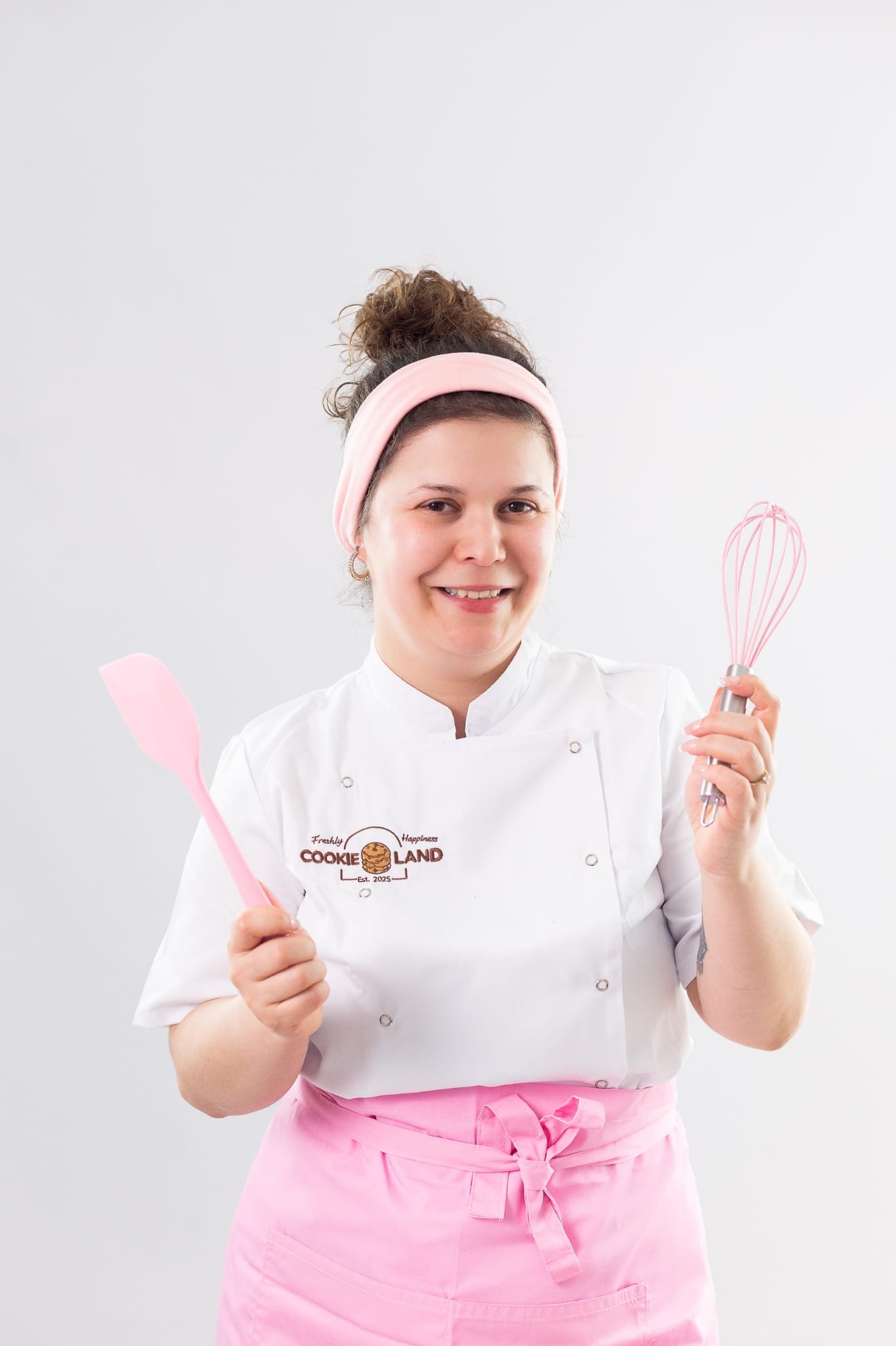 Cookieland founder in her pink apron holding baking utensils